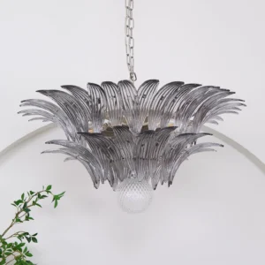 Close-up view of Murano glass palm leaf chandelier with silver chain suspension in minimalist modern interior with plants