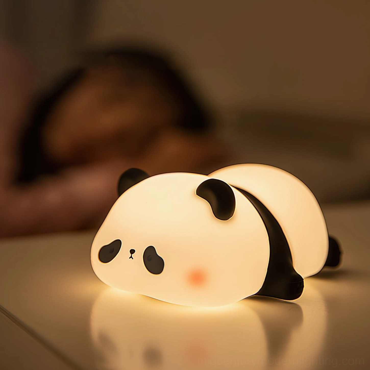 Panda LED night light on bedroom bedside table with warm glow, person sleeping in background