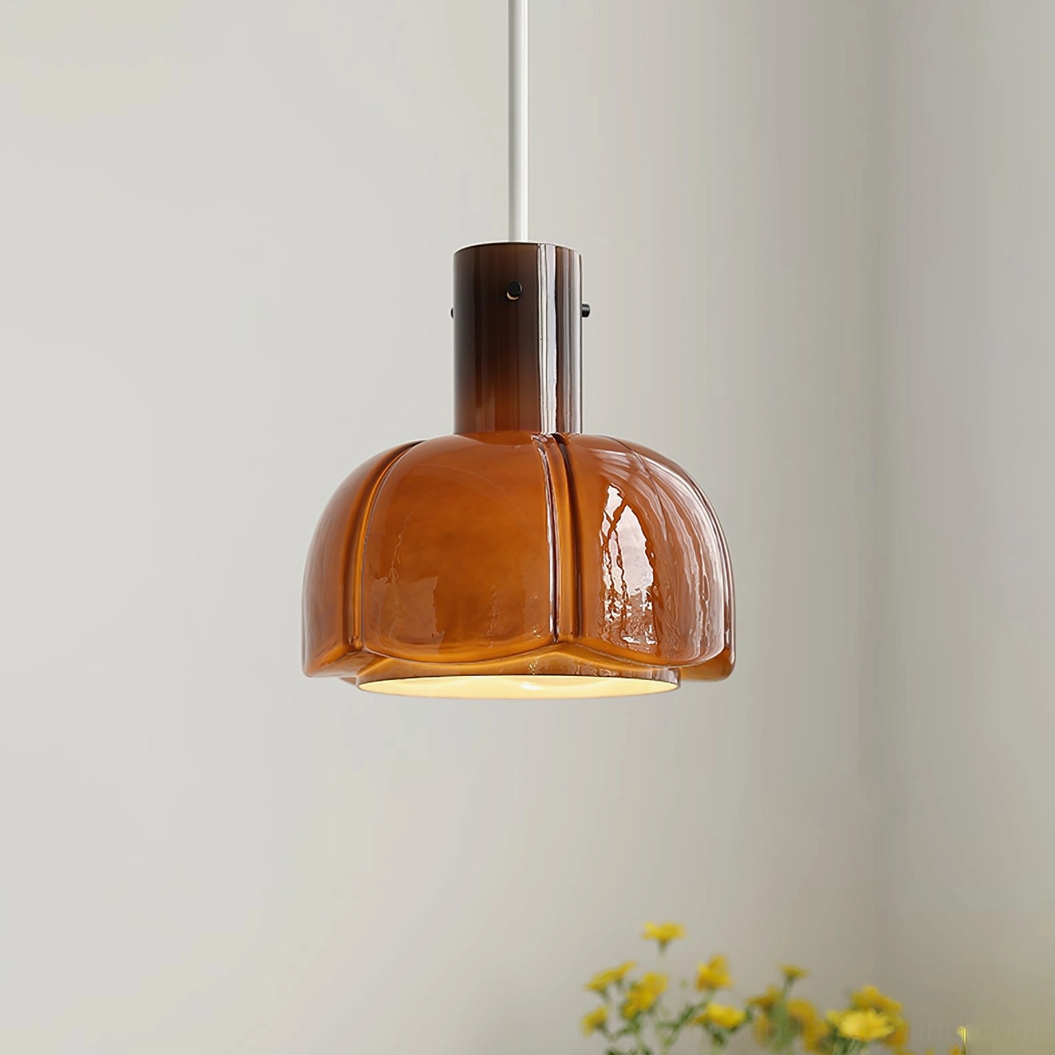 Amber brown Paolina glass pendant light with glossy finish in minimalist indoor space with yellow florals