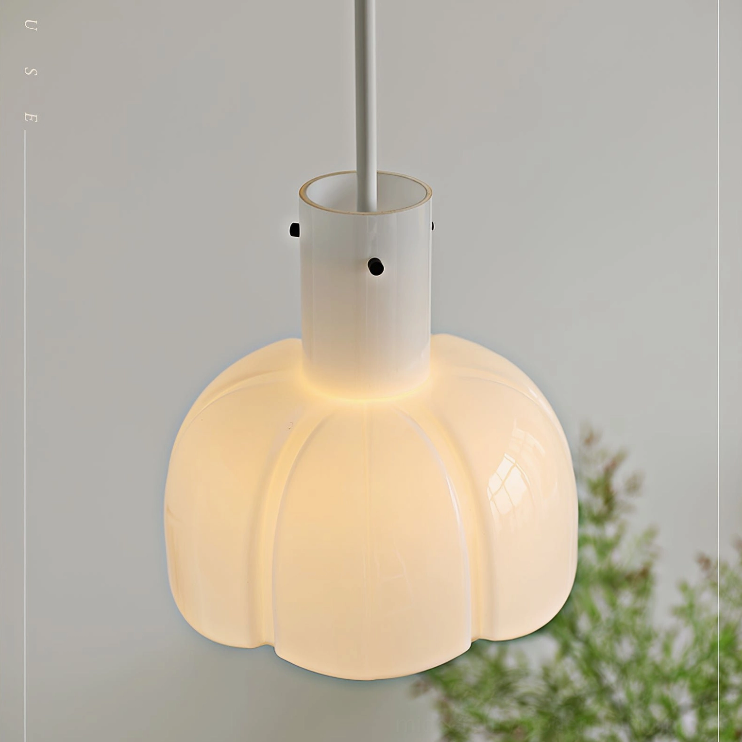 Frosted white Paolina pendant lamp in minimalist indoor space with green plants and text wall decor
