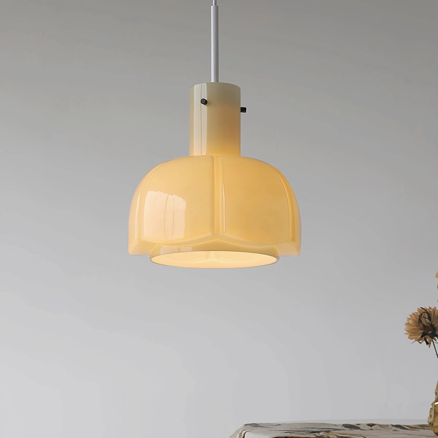 Milky white Paolina pendant lamp three-quarter view against light grey wall with green plant decor