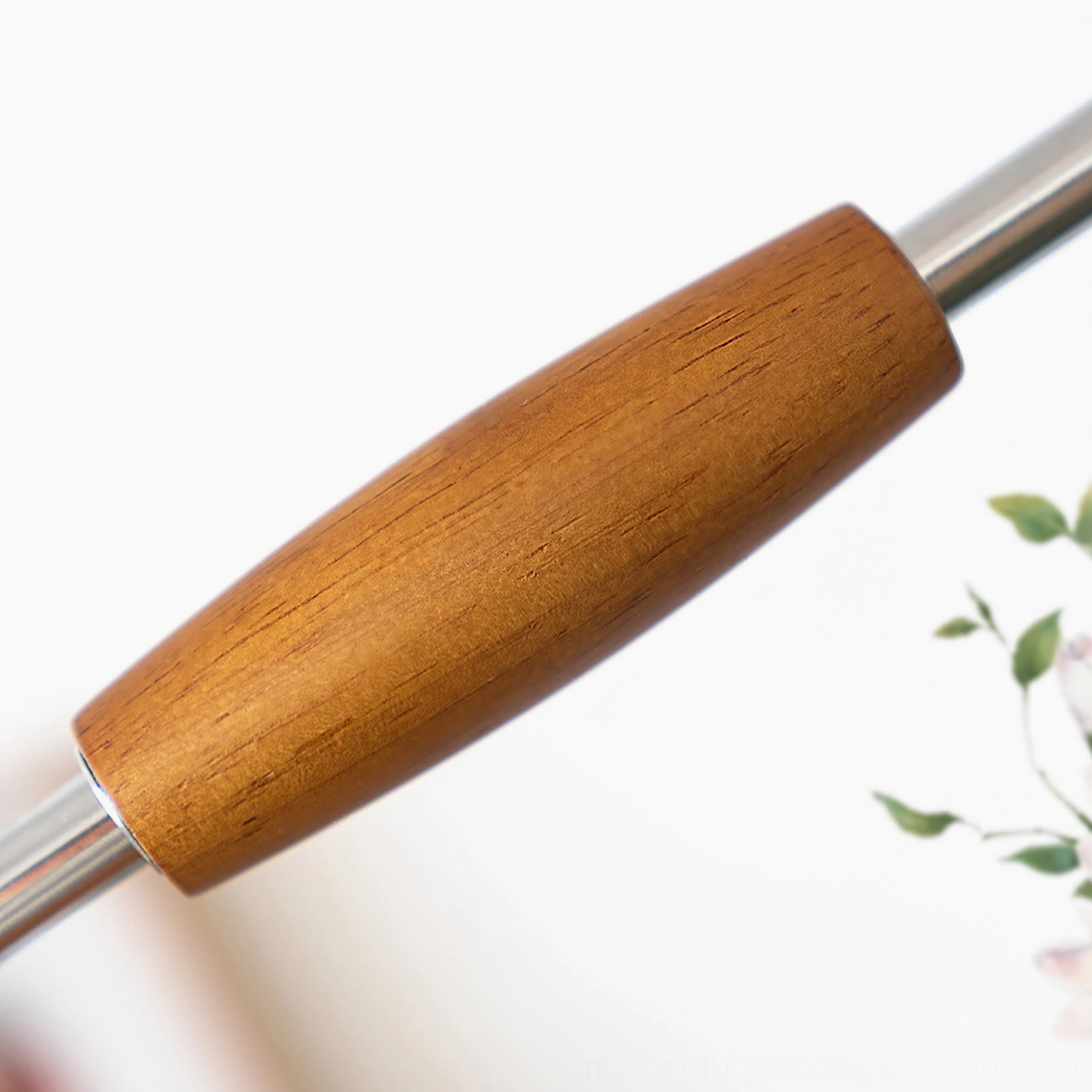 Macro photography of swing arm wall lamp's wooden articulated joint with polished chrome metal connector and smooth wood texture