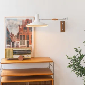 Swing arm wall lamp installed in vintage home interior with wooden side table, retro radio and warm neutral décor styling