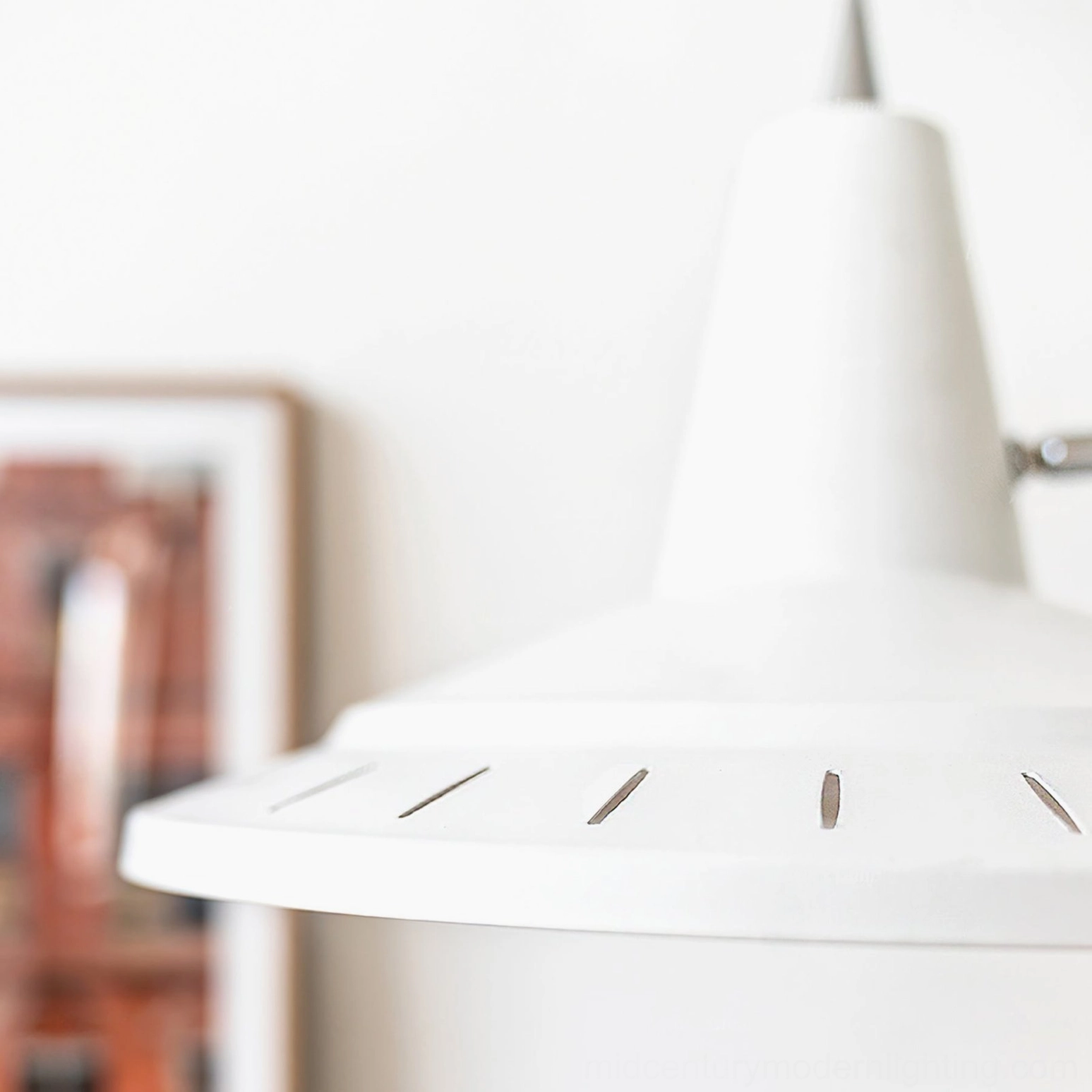 Close-up of white metal lamp shade with ventilation slits for heat dissipation and warm ambient light diffusion