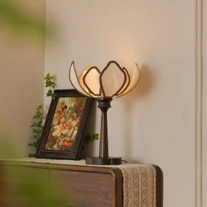 Pauline lotus lamp three-quarter view on vintage wooden dresser with brass decor and botanical paintings, vintage interior styling
