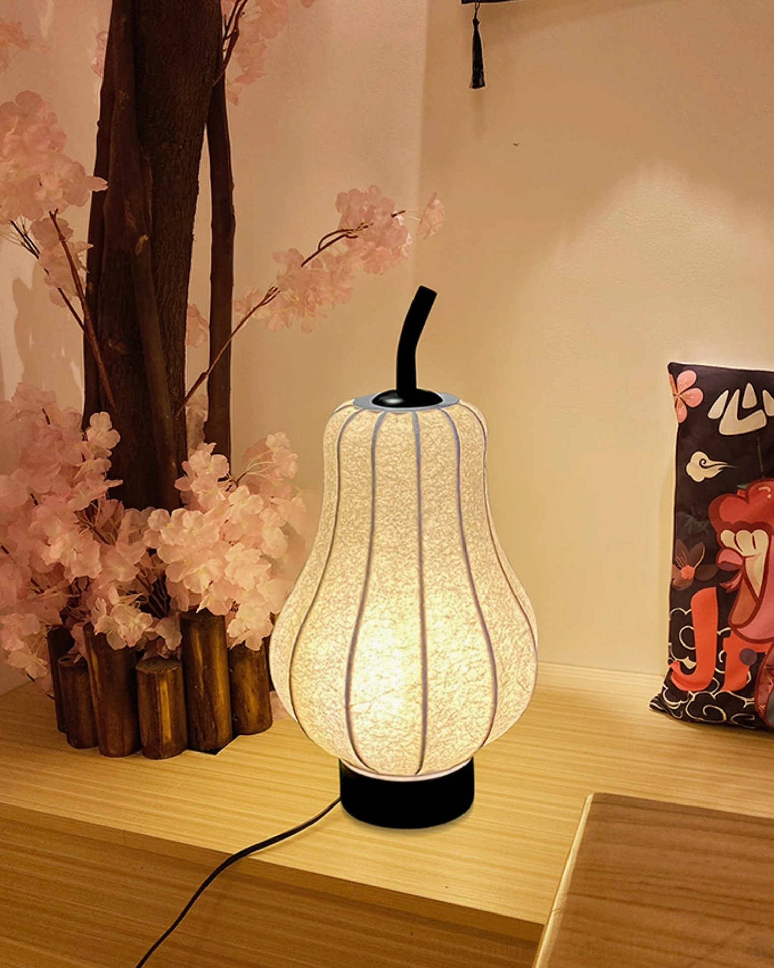 Battery-powered pear table lamp in low wooden living area with cherry blossom decor