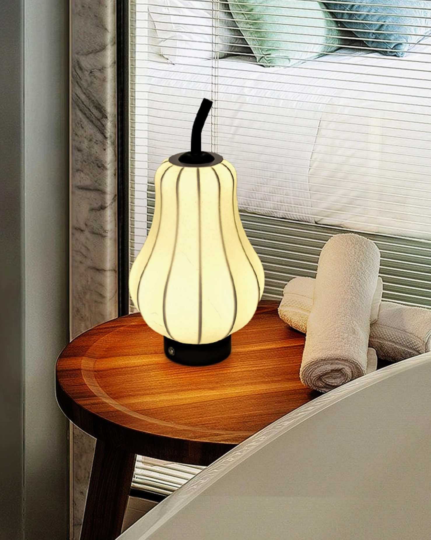 Cordless pear lamp positioned on window-side small table with rolled towels
