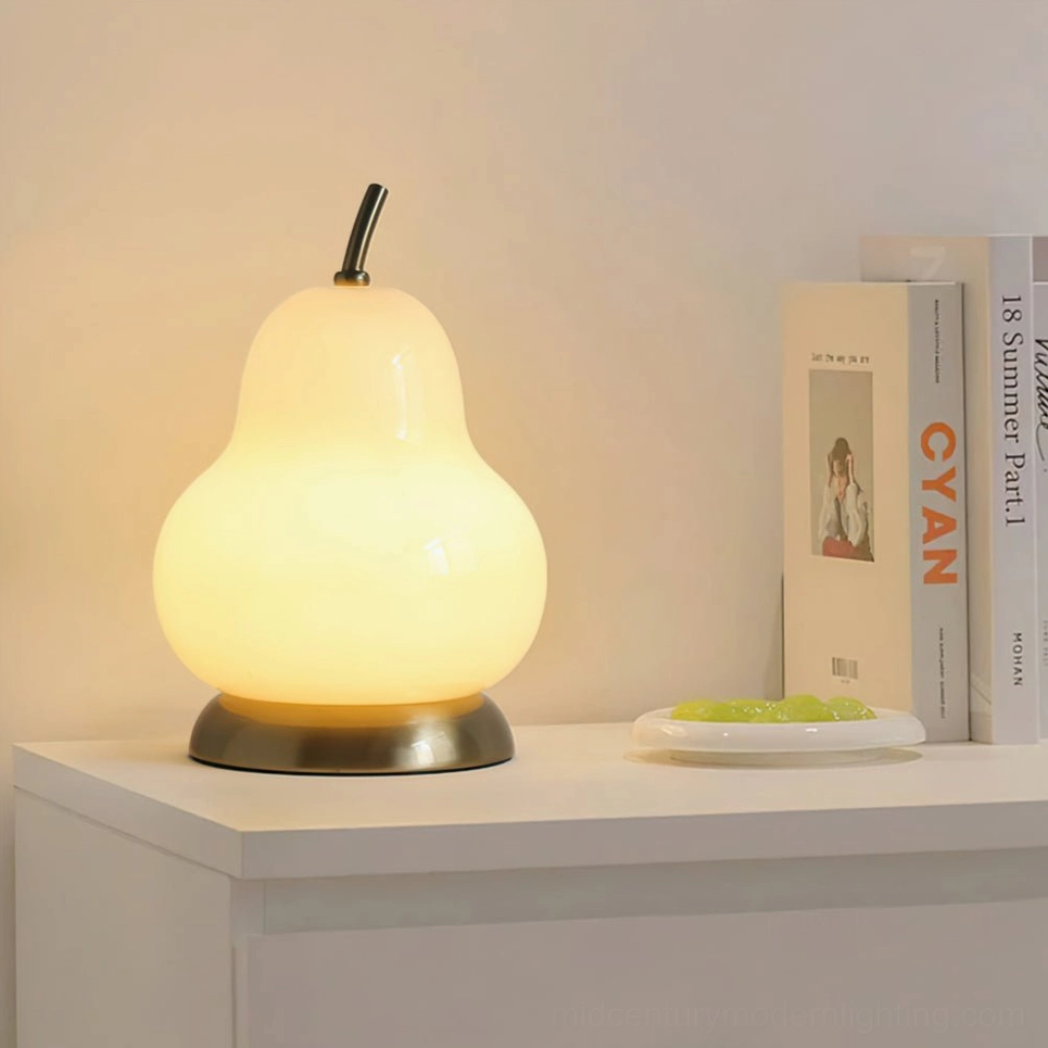 Modern cordless pear lamp illuminated on side table with books, soft warm light creating intimate reading nook