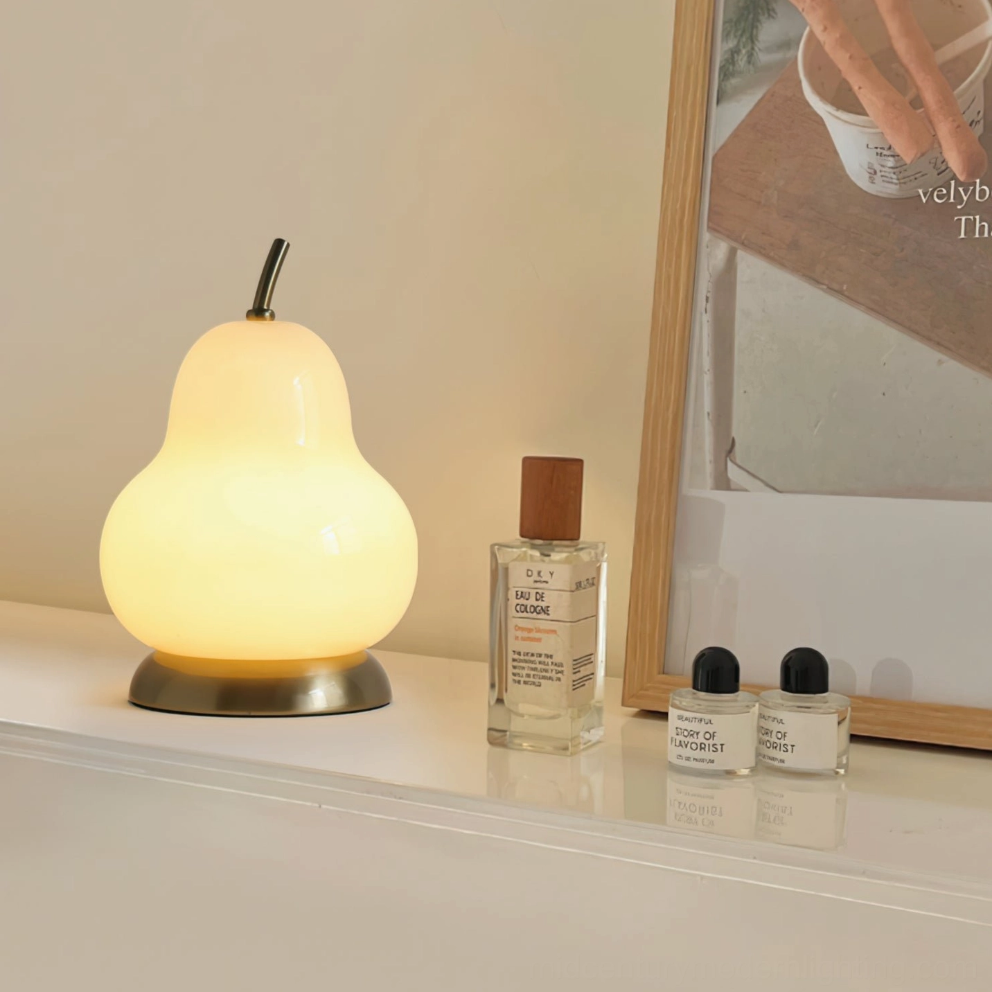 Rechargeable pear glass table lamp glowing on vanity counter with perfume bottles, warm LED illumination