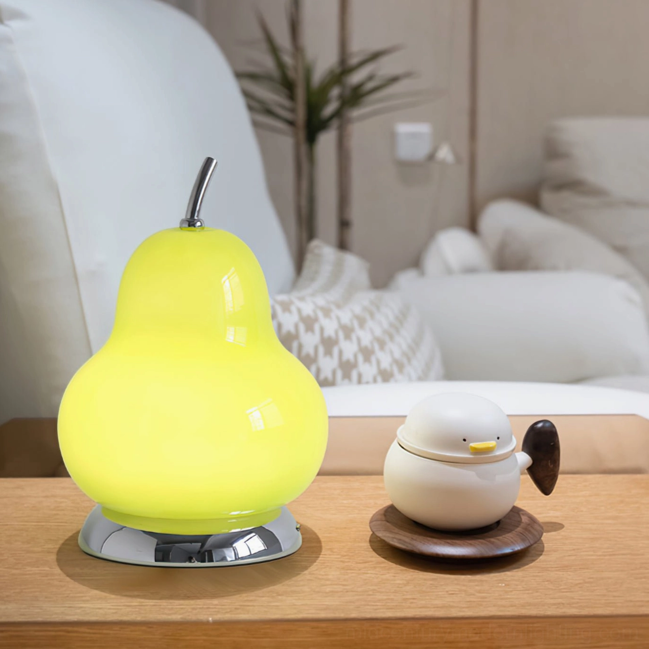 Pear-shaped glass battery lamp displayed on wooden side table with stacked books and fruit bowl, interior styling