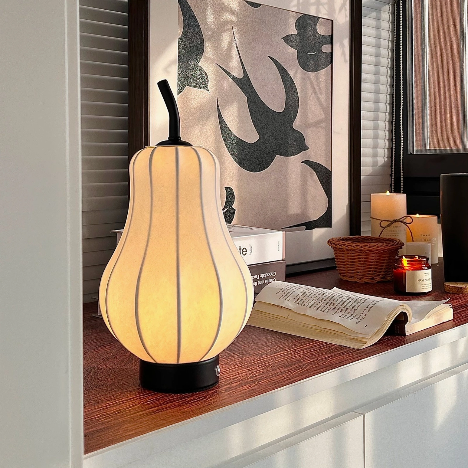 Mid-century modern pear lamp paired with books and candle on wooden countertop