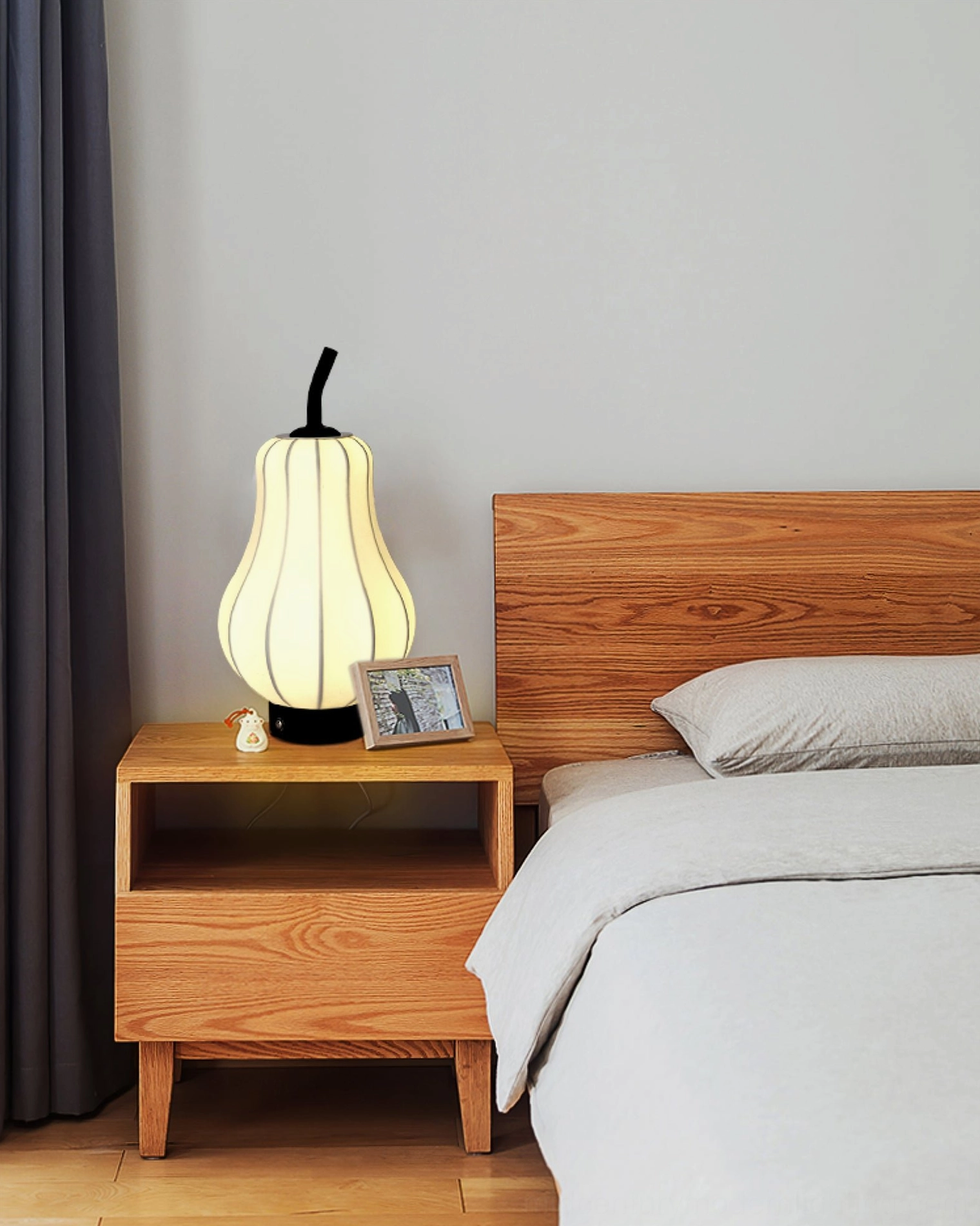 Wireless pear table lamp on wooden nightstand beside bed, bedroom ambient lighting