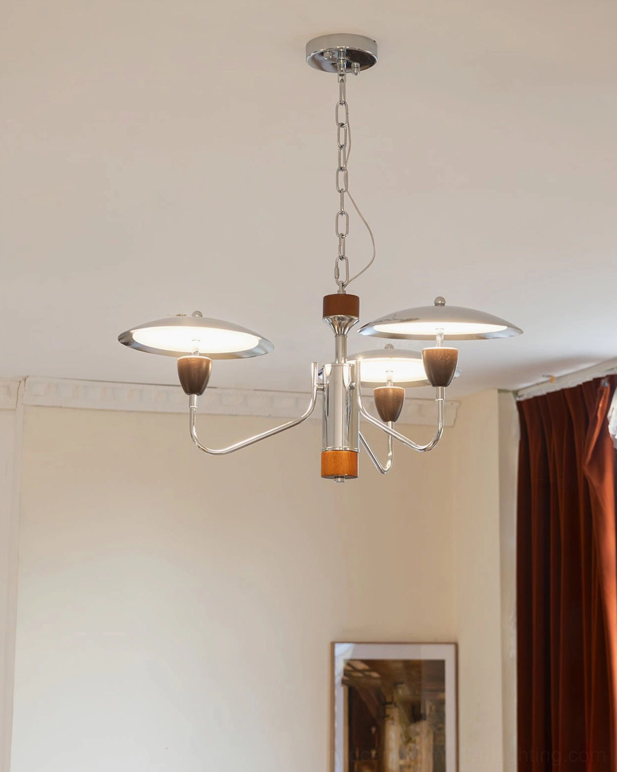 Peggy 4-light chrome chandelier in neutral minimalist living room, eye-level view showing long central pole and walnut wood accents