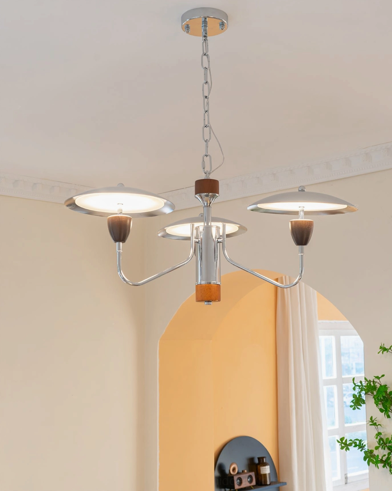 Peggy 4-light lit chandelier glowing in warm arched doorway living space, demonstrating ambient lighting and frosted glass shade diffusion