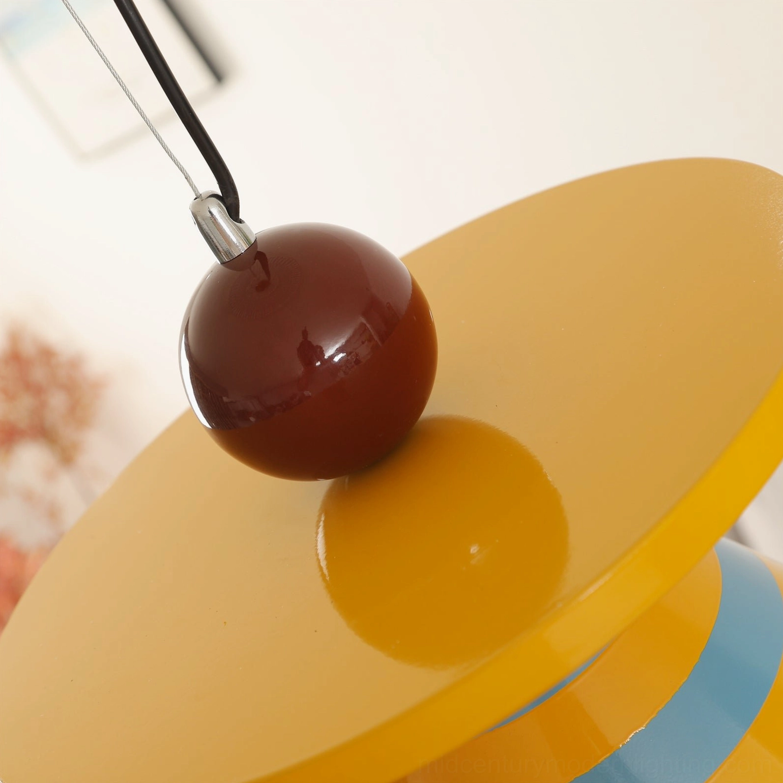 Close-up detail of pendant lamp canopy assembly showing brown spherical finial and polished metal tray hardware