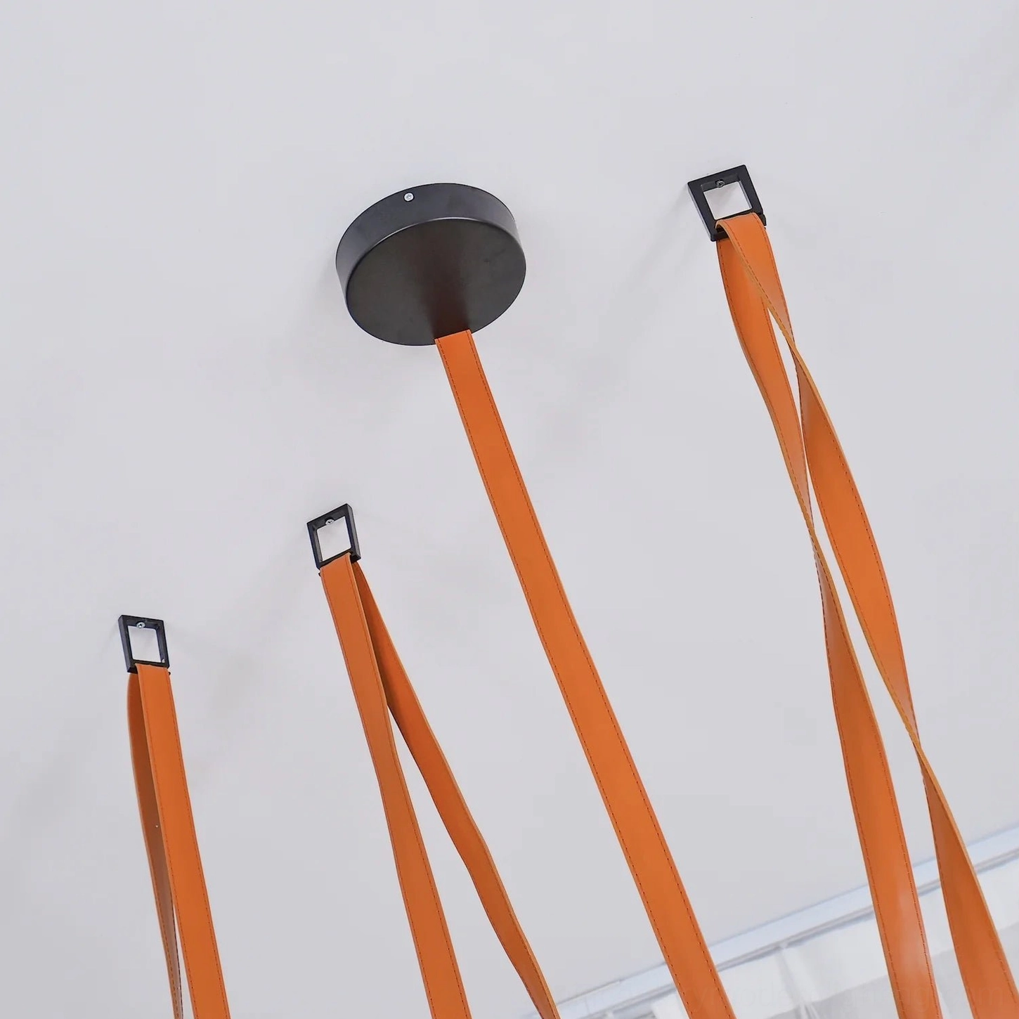 Ceiling mounting hardware for leather sling pendant lamp with black metal fixtures and leather straps