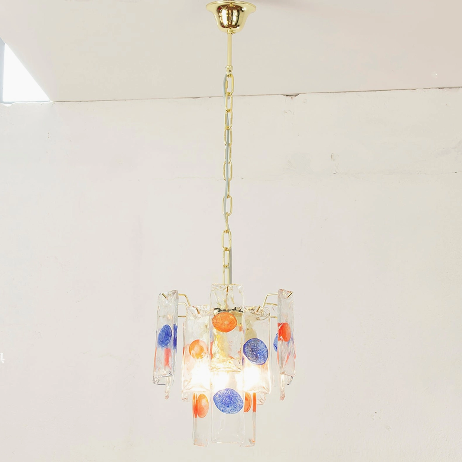 Modern pendant lamp fixture showing intricate craftsmanship of colored glass assembly with gold metal hardware