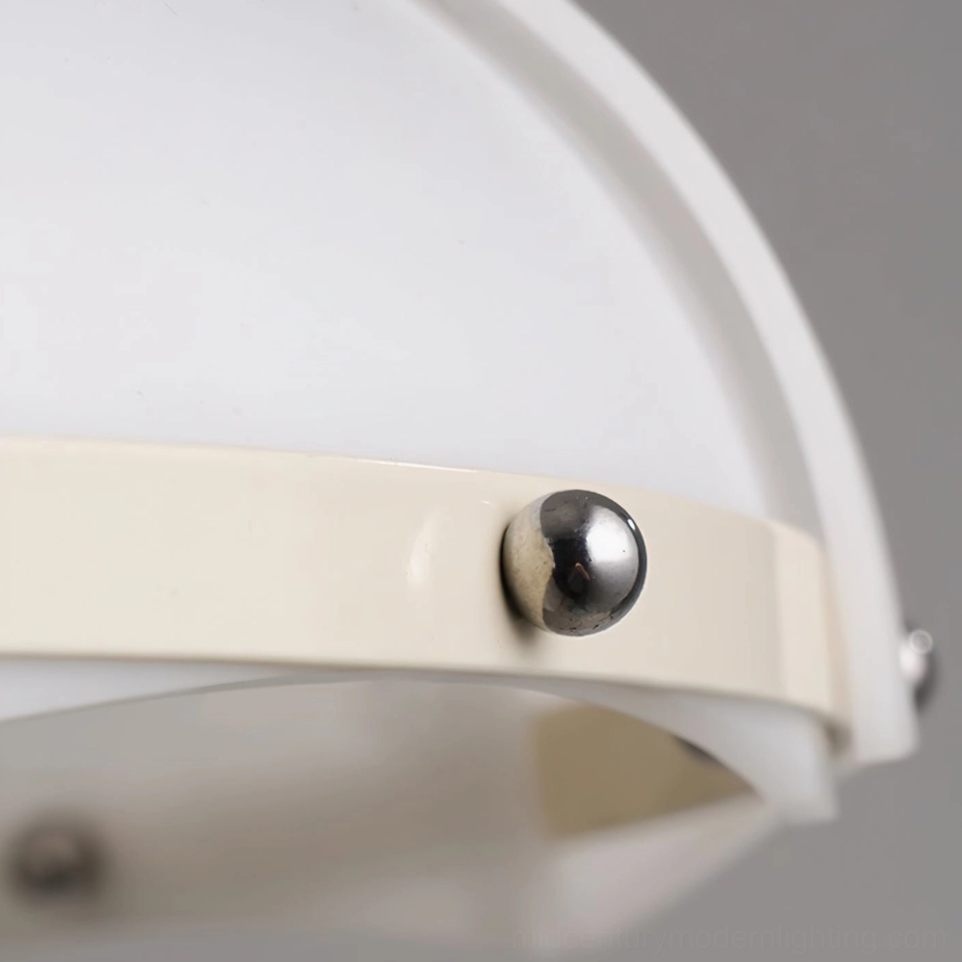 Extreme close-up of swirl pendant lamp shade trim detail with round metal fastener on off-white trim