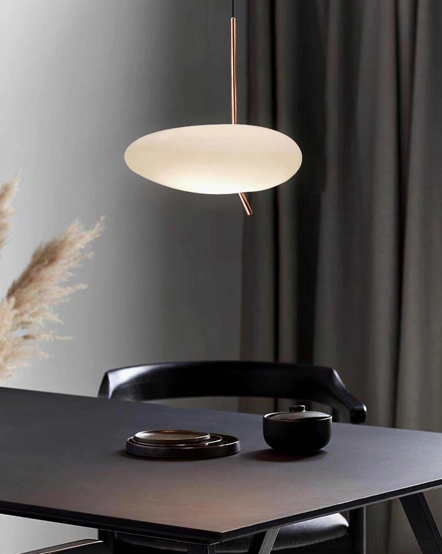 Modern dining room pendant light with low front view, dark dining table and pampas grass tableware decor
