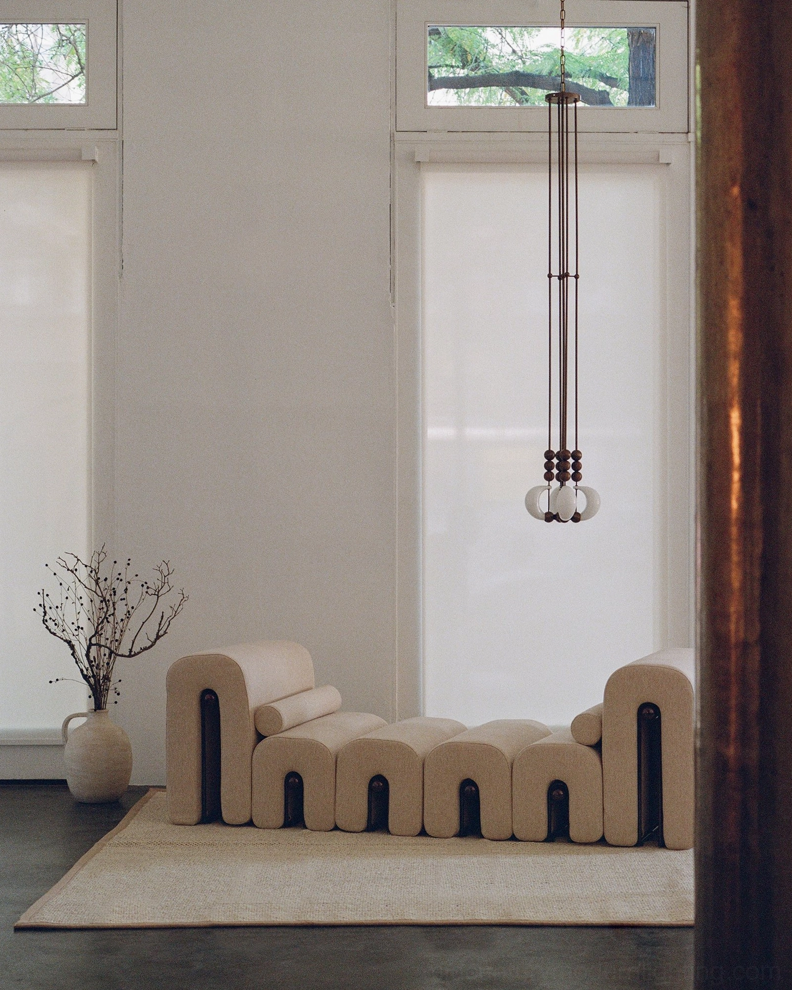 Bent glass pendant light suspended in minimalist modern living room interior - warm light ambiance over seating area