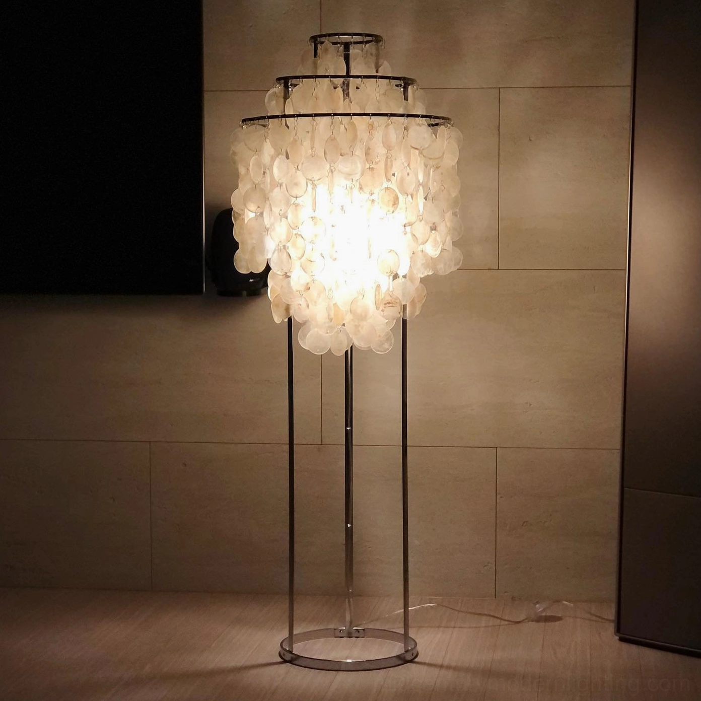 Mother of pearl shell floor lamp with lit tiered pendants and round chrome base in dark modern living room