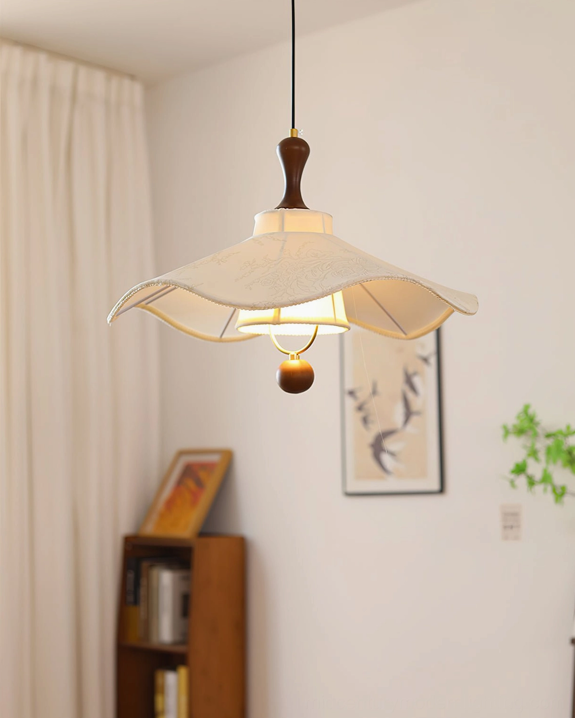 Illuminated Pendolo fabric pendant light in dining room setting with warm glow and wooden hardware