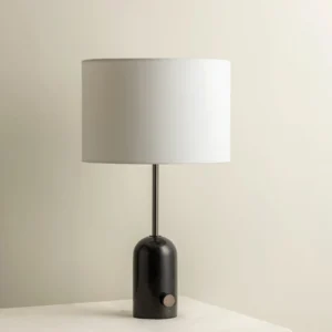 Black marble Penn table lamp with brass metal stem on beige tablecloth, minimalist design perspective
