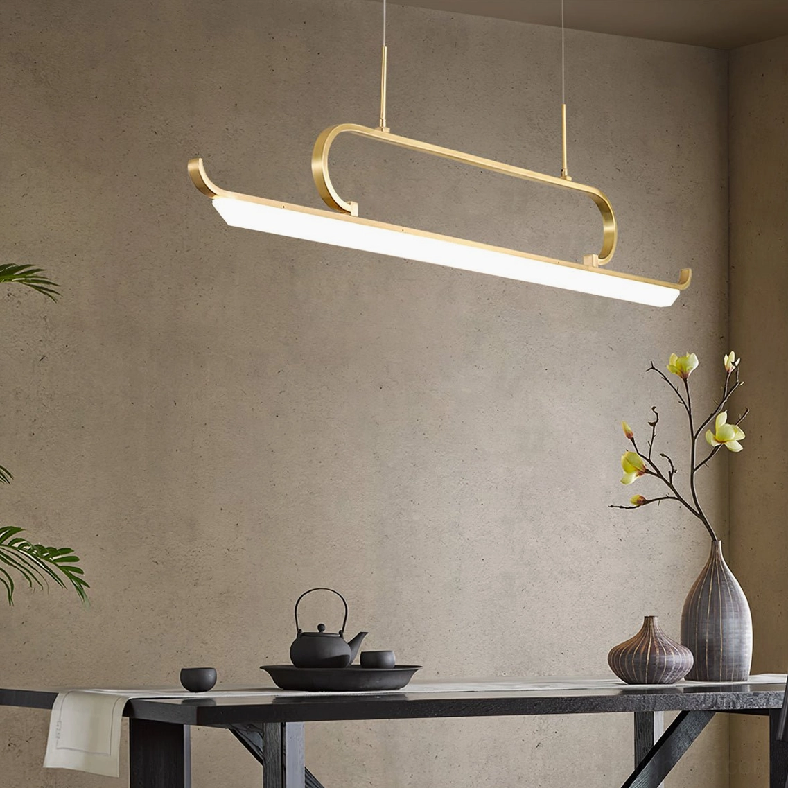 Penna brass gold chandelier over minimalist tea table with decorative floral vase, three-quarter view