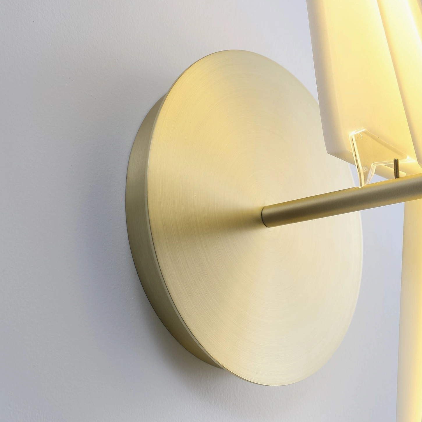 Close-up detail of perching bird wall lamp showing brushed brass gold metal base, mounting hardware, and acrylic construction