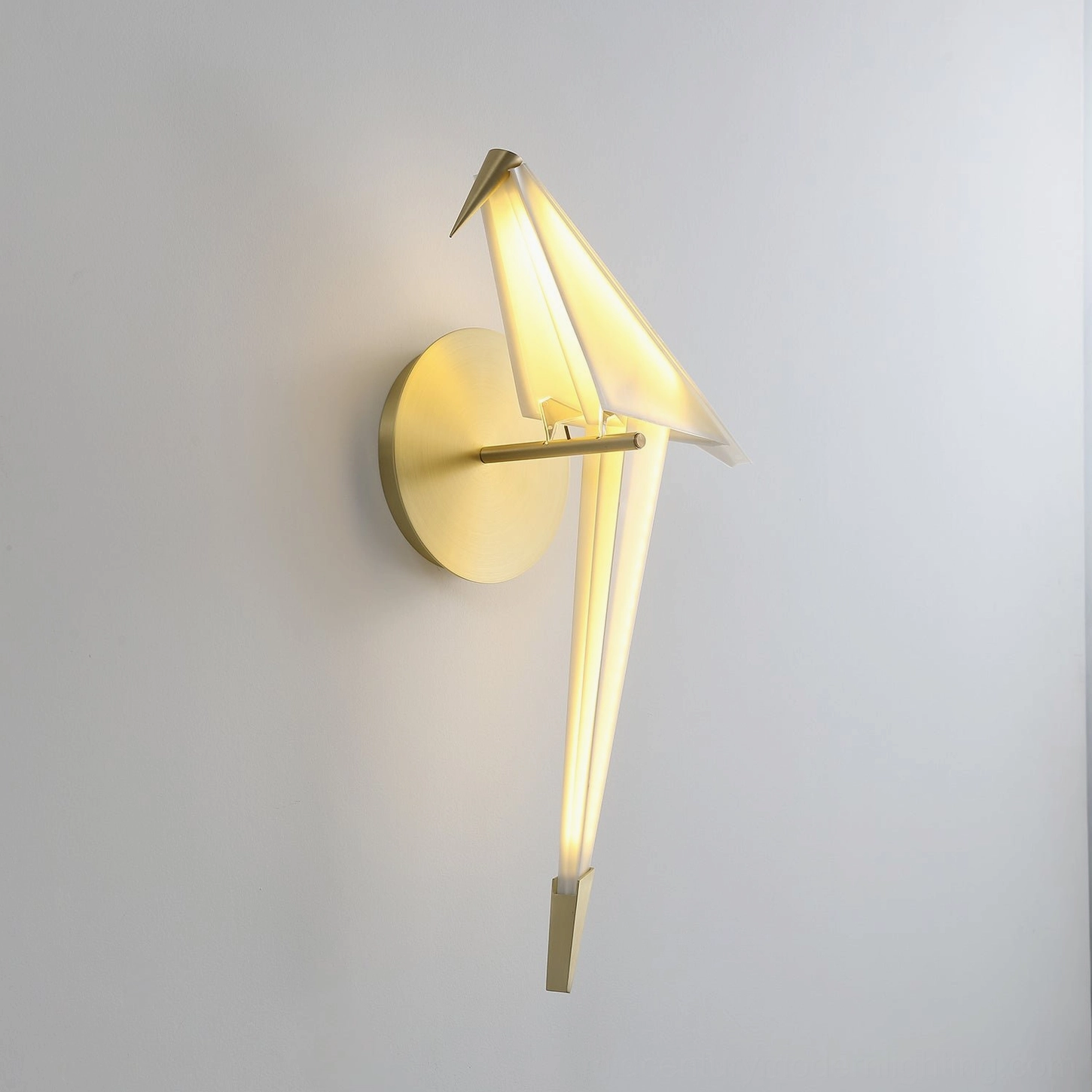 Perching bird wall lamp origami-inspired bird silhouette with brass gold mount and warm glowing light on light grey background