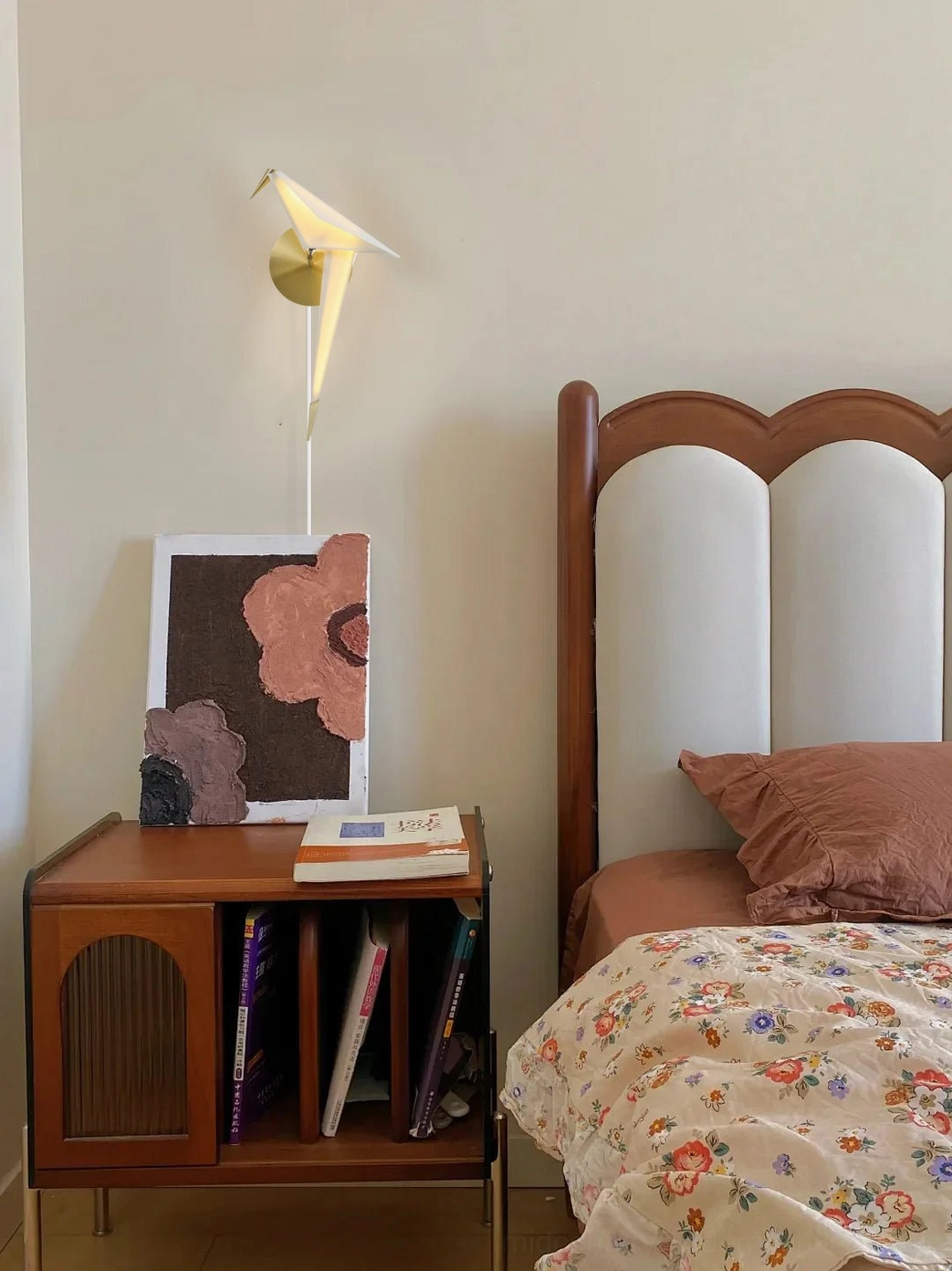 Perching Bird wall lamp in cozy vintage bedroom with wooden side cabinet and decorative artwork warm light ambiance