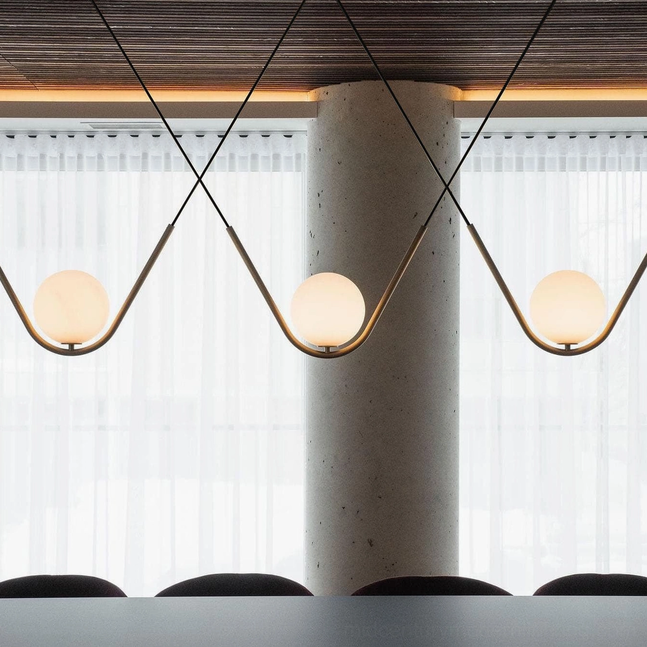 Perle multi-globe pendant light low angle view with minimalist dining space and sheer curtains