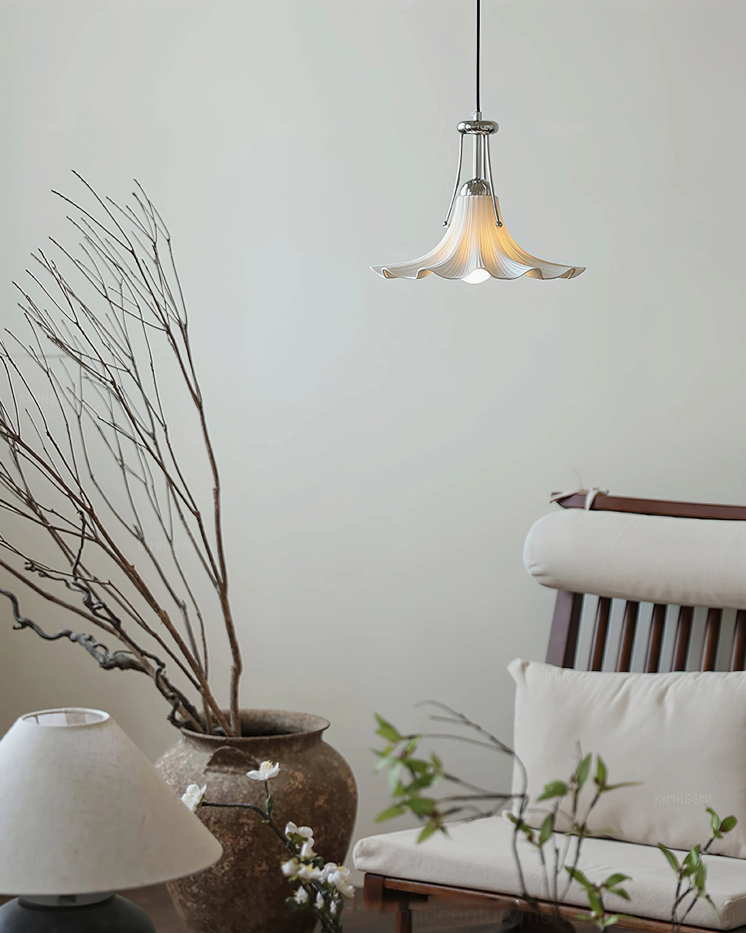 Petalia ceramic pendant light glowing warmly above wooden chair in minimalist living area with botanical decor