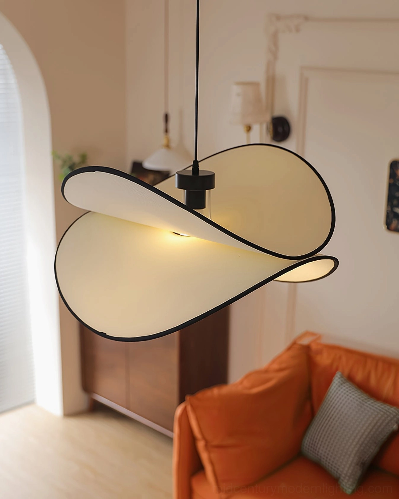Petalo ceiling pendant glowing warm light above orange sofa in contemporary living room
