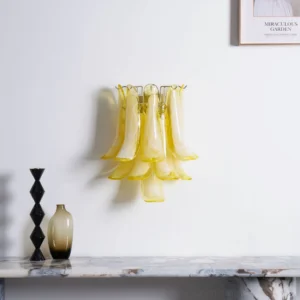 Petral wall sconce with warm yellow glass petals installed in minimalist entryway above marble console table, ambient lighting