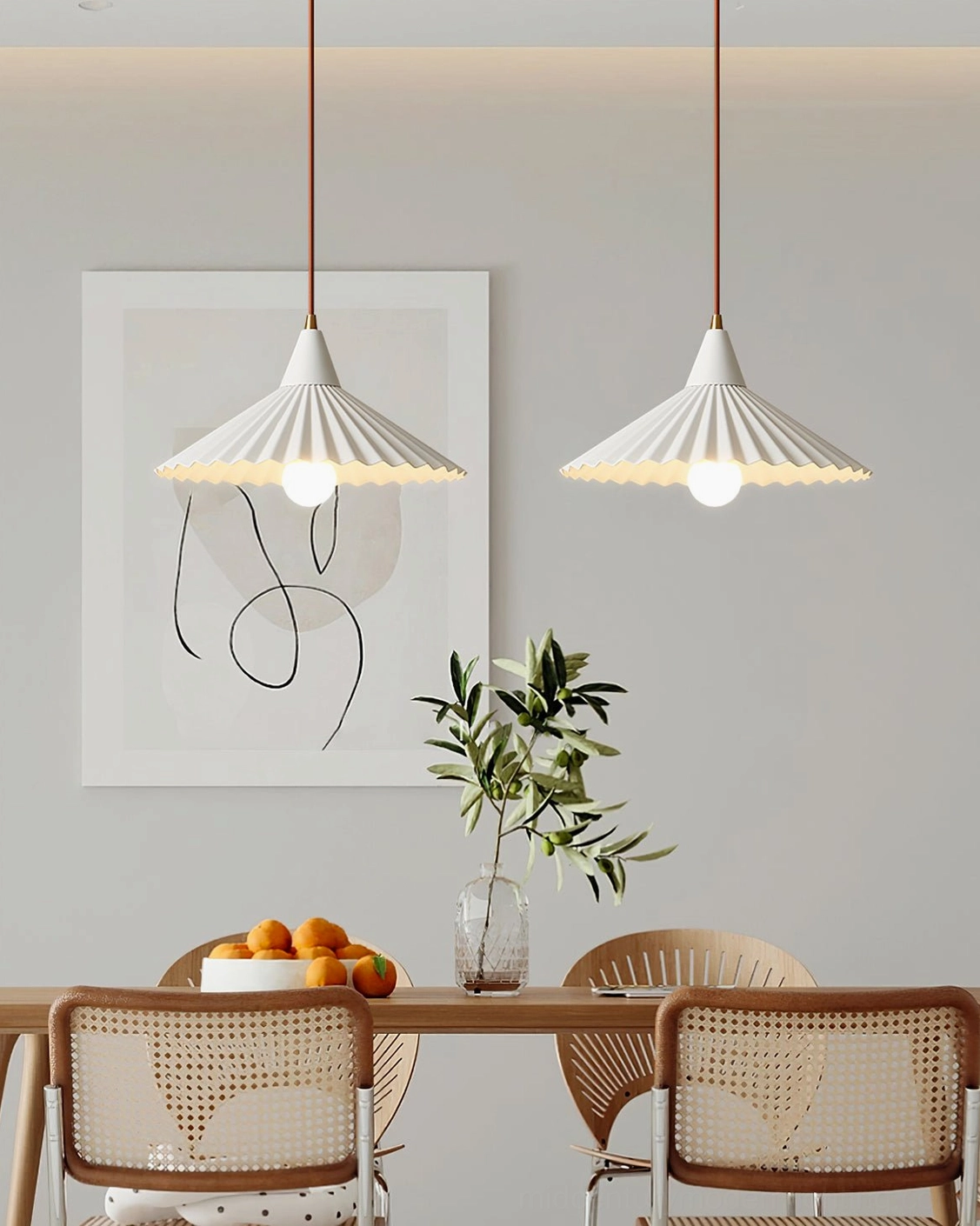 Two matching white Pieghe pendant lights above long dining table with rattan chairs and green tabletop accents