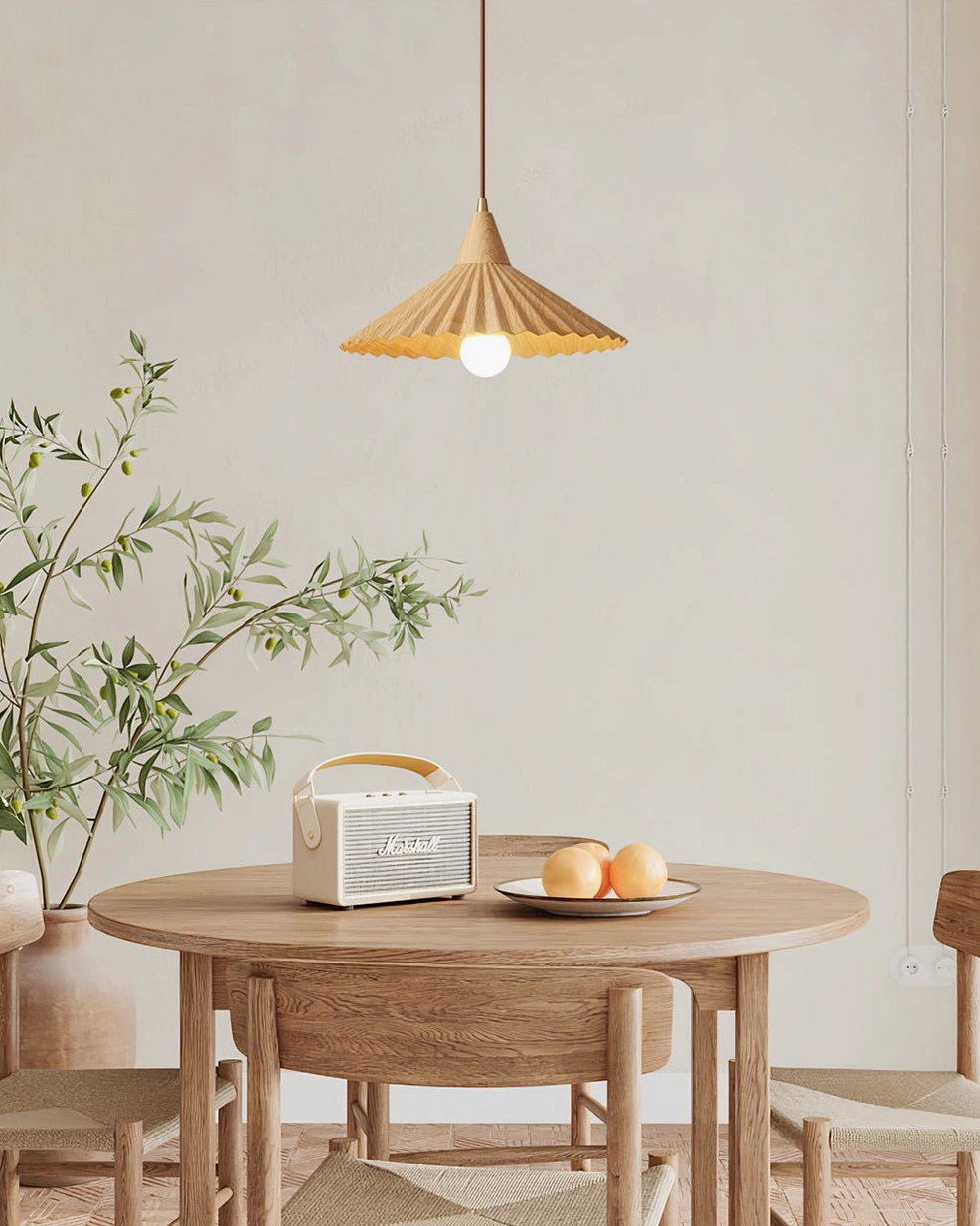 Wood-finish Pieghe pendant lamp above round wooden dining table with potted green plant and table décor