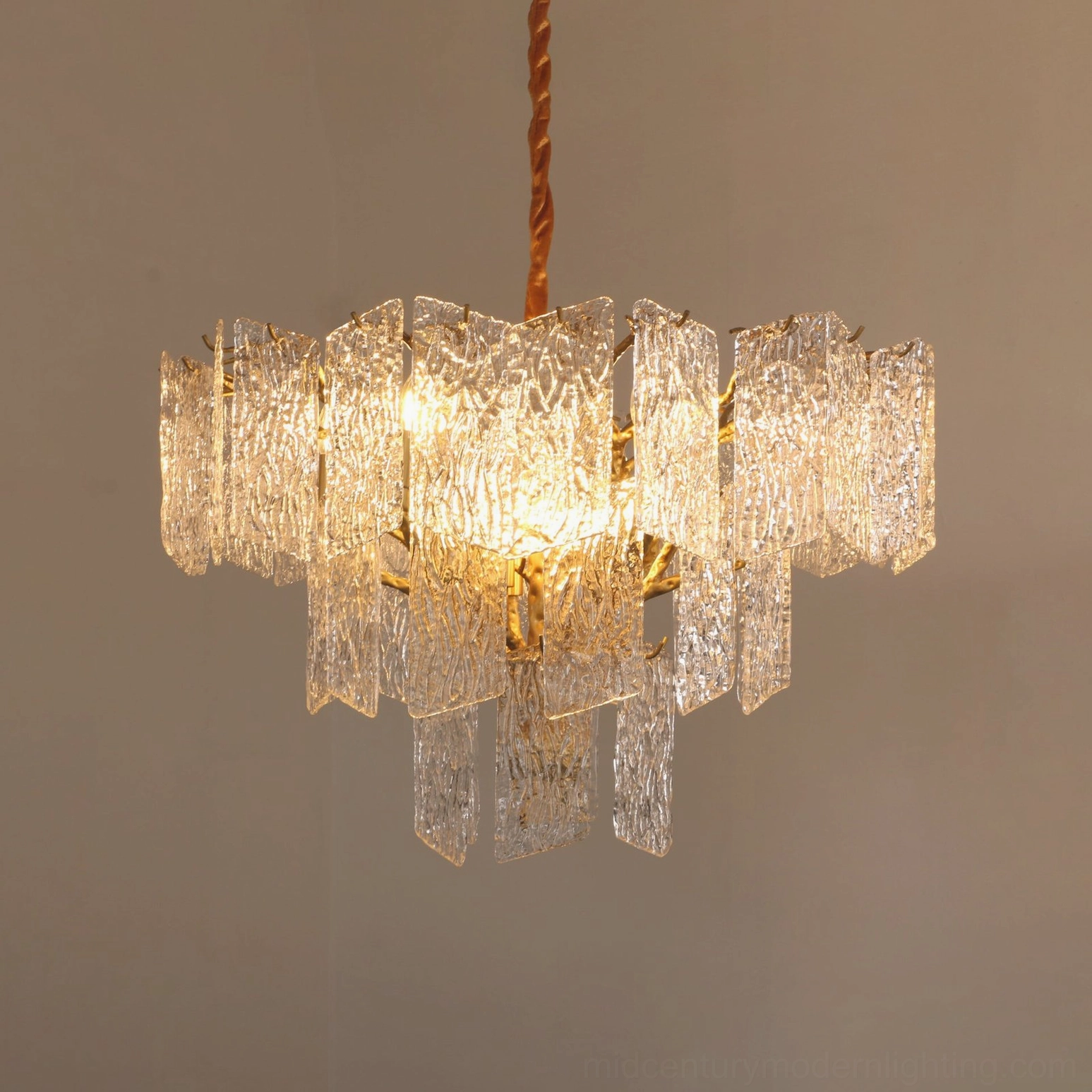 Piemonte chandelier detail shot showing warm LED illumination through rippled glass panels and golden brass branches