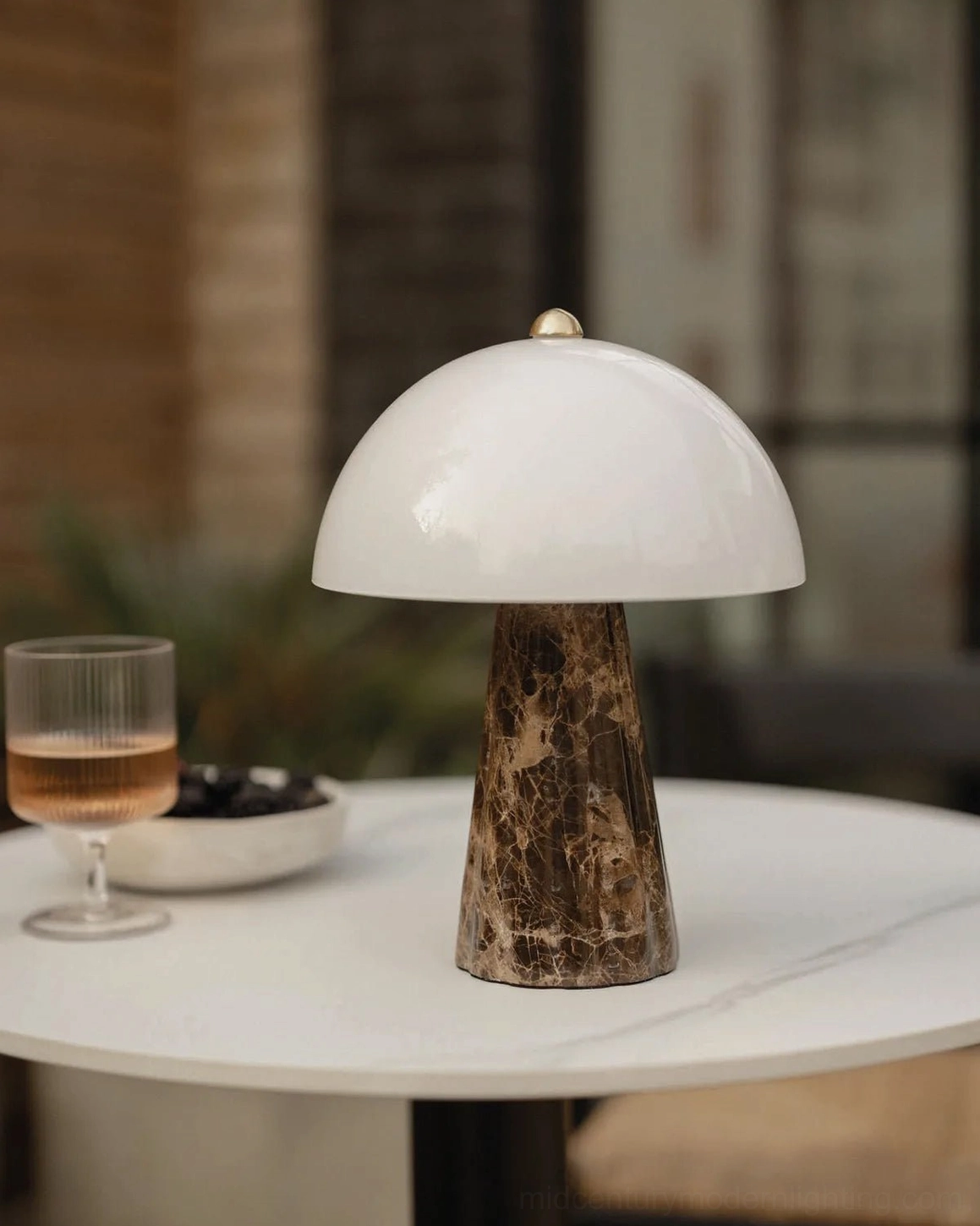 Contemporary table lamp with natural veined marble base displayed on home side table with wine glass and snacks