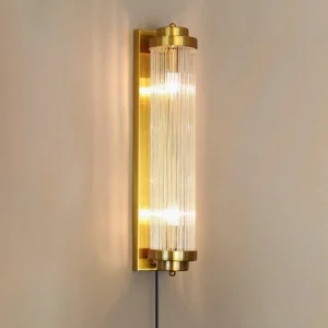 Tall mid-century modern wall sconce illuminated with warm ambient light, side detail showing exposed cord and plug