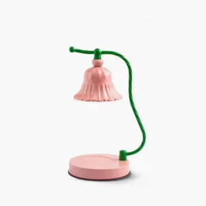 Blush pink fluted ceramic table lamp with green metal arm, front studio view on white background