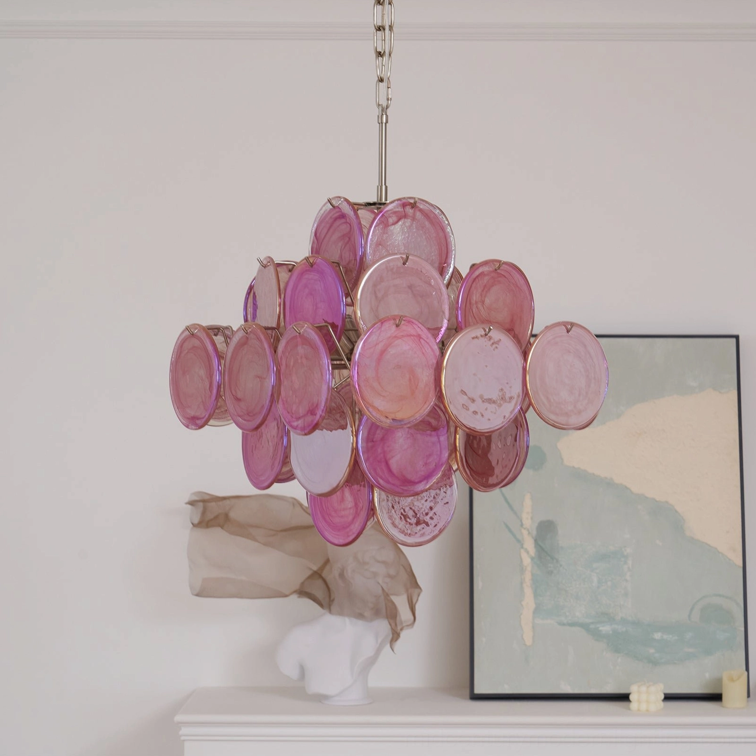 Mauve pink disc chandelier installed in minimalist modern luxury living room above console table with art deco accessories