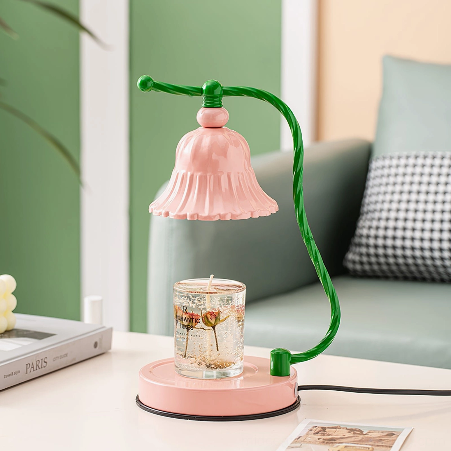 Pink ceramic lamp on sofa side table with purple scented candle and checkered throw pillow background
