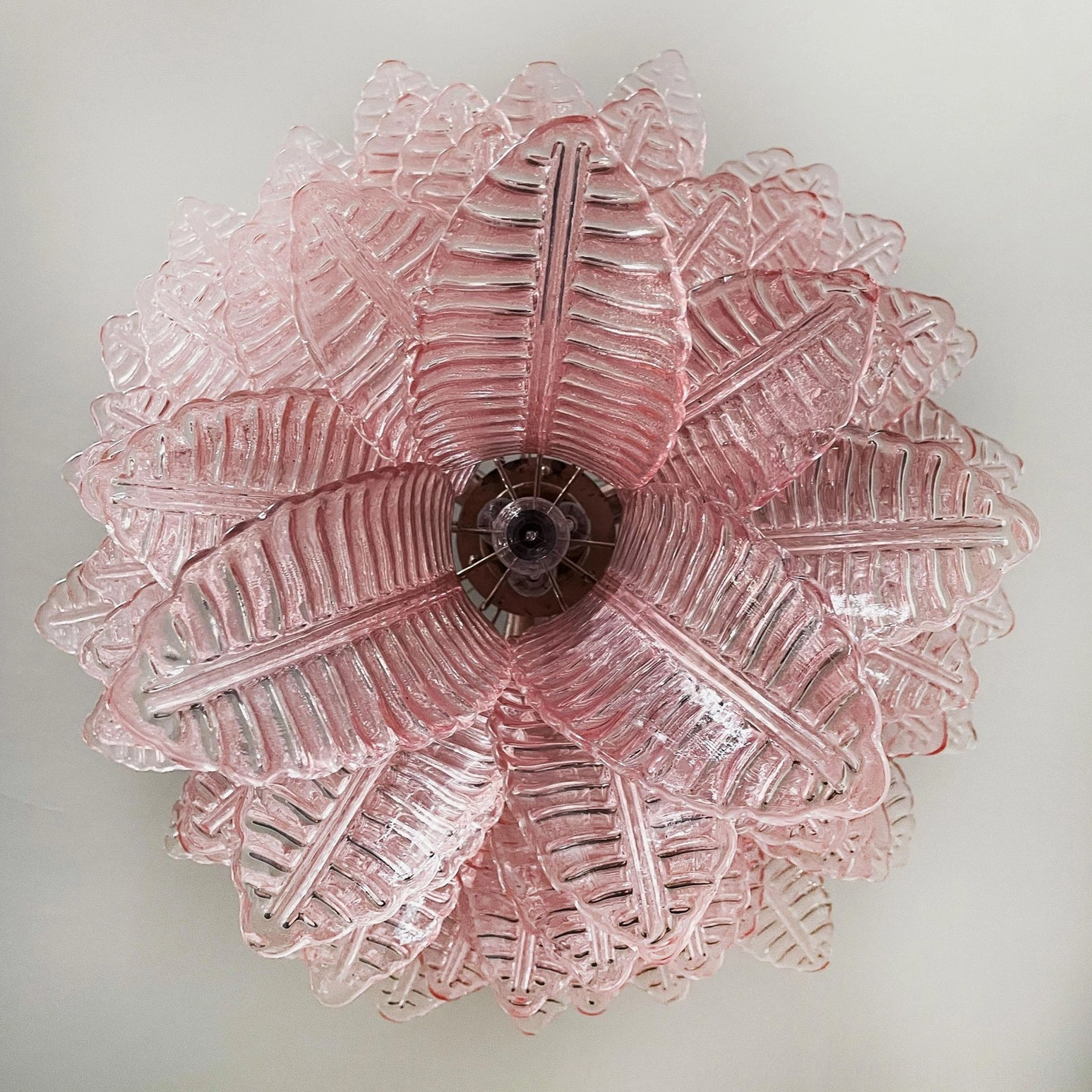 Pink Murano chandelier suspended from decorative ceiling with ambient lighting effect