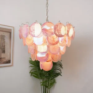 Pink Murano disc chandelier installed in modern home interior corner with warm ambient lighting, three-quarter angle view