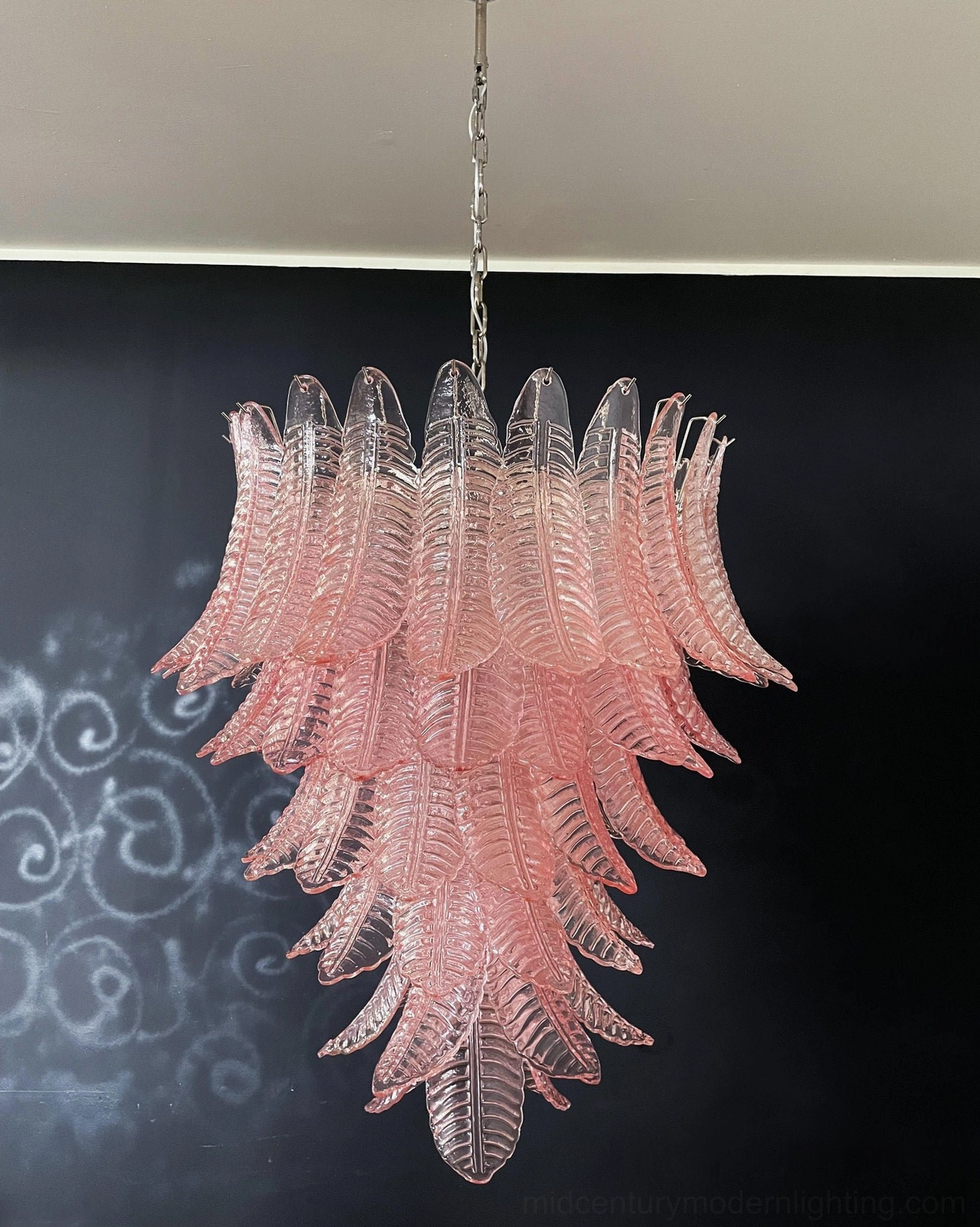 Pink ombre Murano glass chandelier frontal view against dark decorative wall