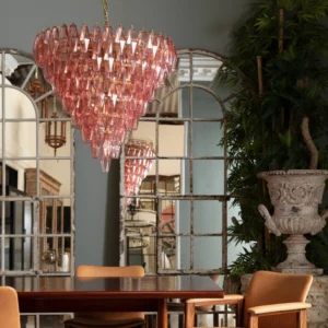 Pink tiered crystal chandelier installed in romantic vintage dining room with arched mirror and dining table