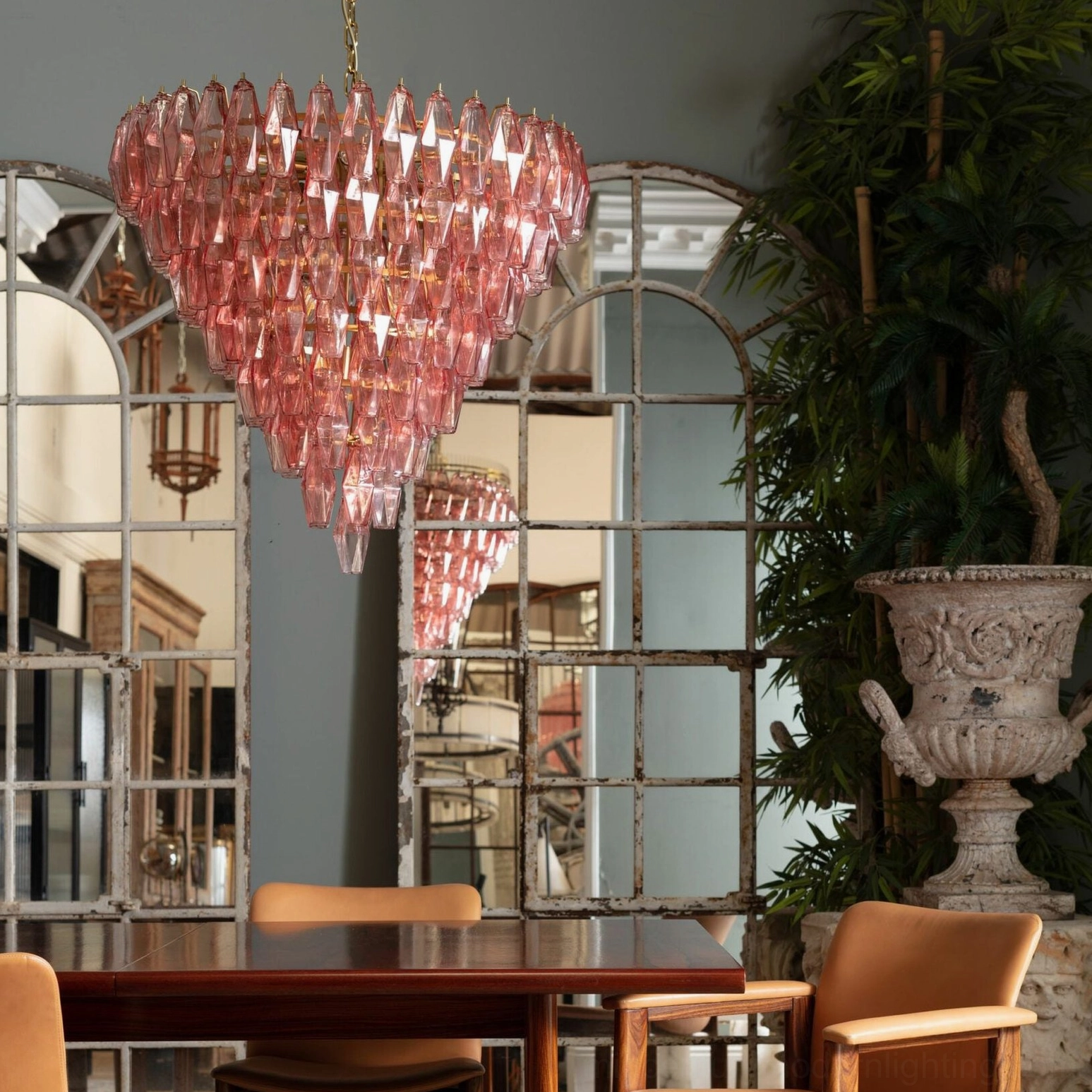 Pink tiered crystal chandelier installed in romantic vintage dining room with arched mirror and dining table