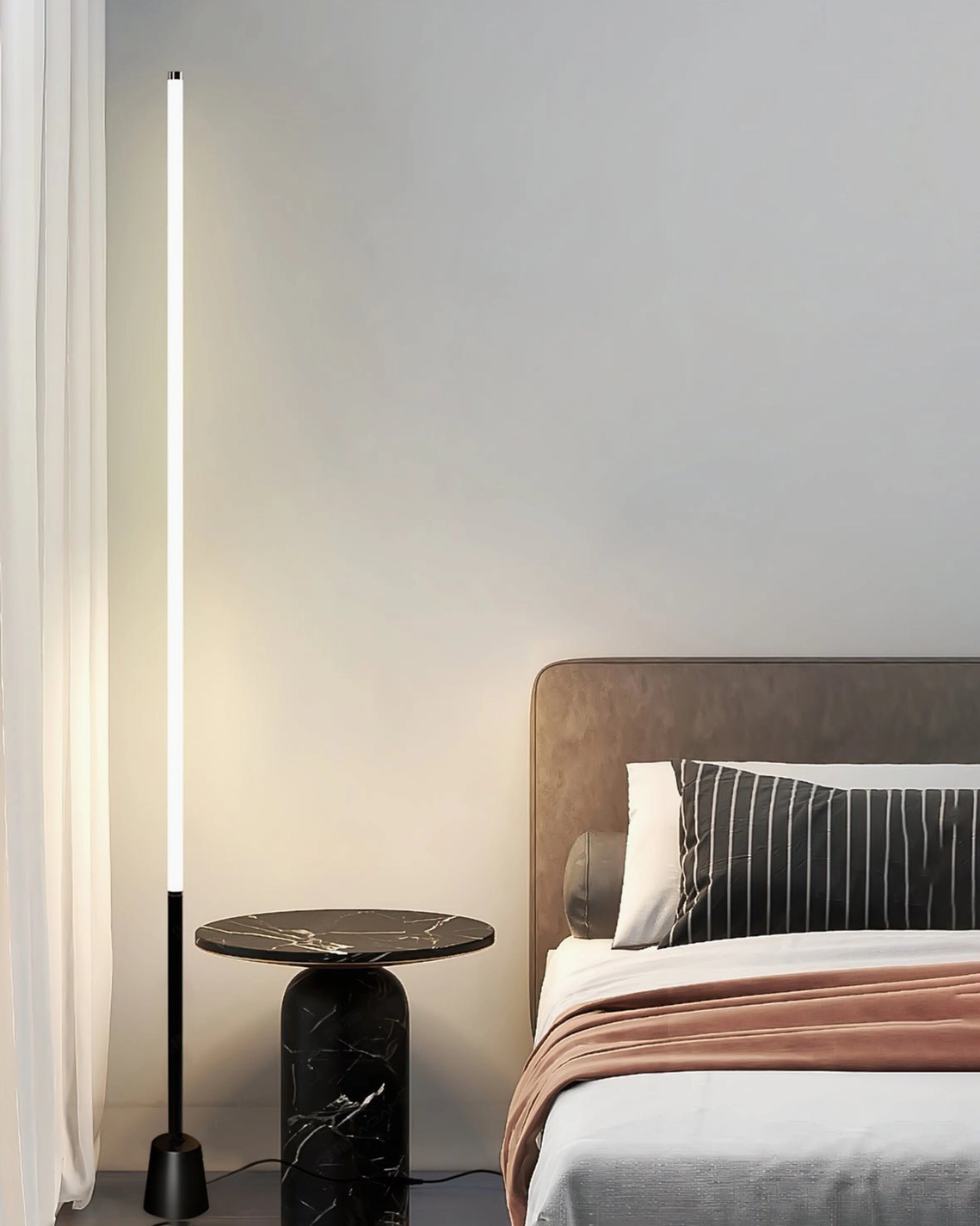 Pipeline minimalist floor lamp with black base in bedroom setting, beside marble side table and bed, modern bedroom lighting