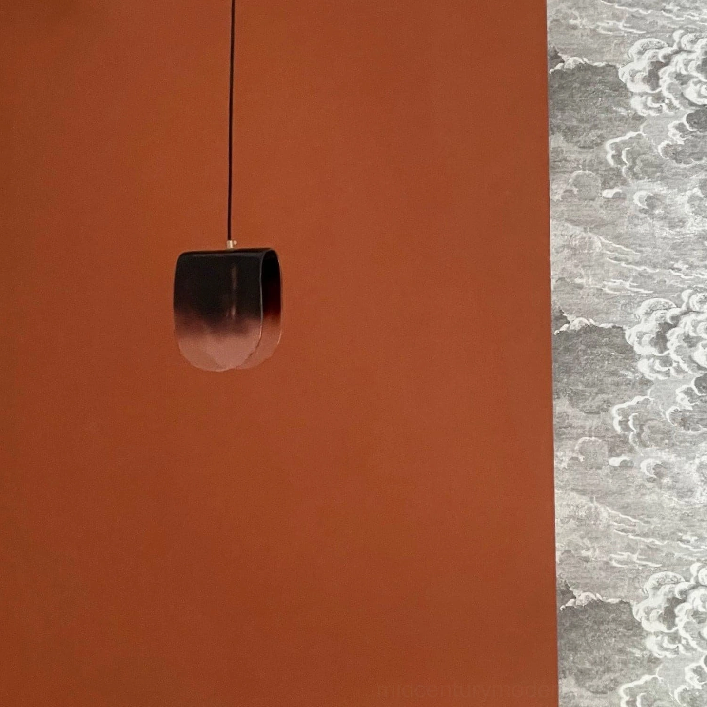 Compact hand-blown glass pendant light shown beside decorative patterned rug and terracotta accent wall